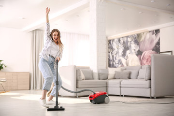 Wall Mural - Young woman having fun while vacuuming at home