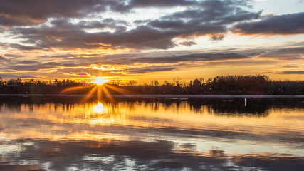 The sun bursts through the clouds at dawn on Blue Marsh Lake in Berks County, PA