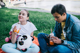 Fototapeta Londyn - Teenage boy and little girl drinking juice and watching smartphone