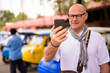 © Ranta Images - Portrait of happy senior tourist man using phone in Ayutthaya