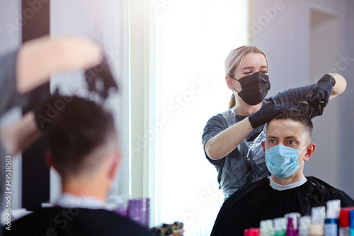 Hairdresser with security measures for Covid-19, cuts hair with a scissors to a man in a medicine mask, social distance, cutting hair with a medical mask and rubber gloves