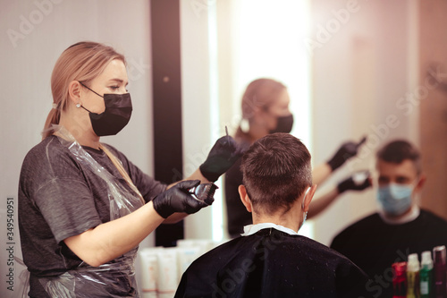 Hairdresser with security measures for Covid-19, cuts a man in a medicine mask, social distance, cutting hair with a medical mask and rubber gloves.
