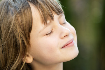 Canvas Print - Portrait of young pretty child girl with long hair enjoying warm sunny day in summer outdoors. Cute female kid relaxing on fresh air outside.