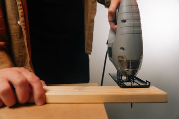 A man uses a tool to saw a tree. The concept of carpentry. Worker in a woodworking workshop