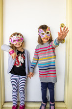 Two Young Girls Smiling And Wearing Colorful Masks.