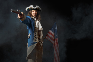 Wall Mural - Man in form of officer of United States Revolutionary War with a flag and gun. July 4th, Independence Day USA Concept. Studio photo on black background