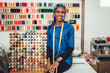 Portrait of happy african dressmaker woman in studio. Background of colorful sewing thread.