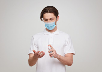 European man in a mask disinfects his hands. Conceptual photo on the theme of the covid-2019 pandemic.