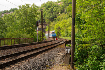 
the train passes through the Czech countryside in the woods on the tracks are stones