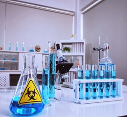 virus vaccine in laboratory concept. glass flask, test tube, and microscope on the table in science laboratory with biohazard sign 