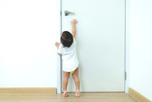 1 Year Old Toddler Asian Baby Boy Standing On Tiptoes Reaching Up Try To Open Door Knob,Security And Safety Child Concept.