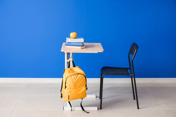 Modern school desk near color wall