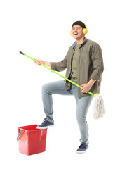 Wall Mural - Young Asian man with mop and headphones having fun on white background