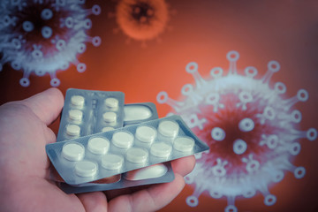 Pills in a man’s hand against the background of the image of a coronavirus. Healthcare concept.