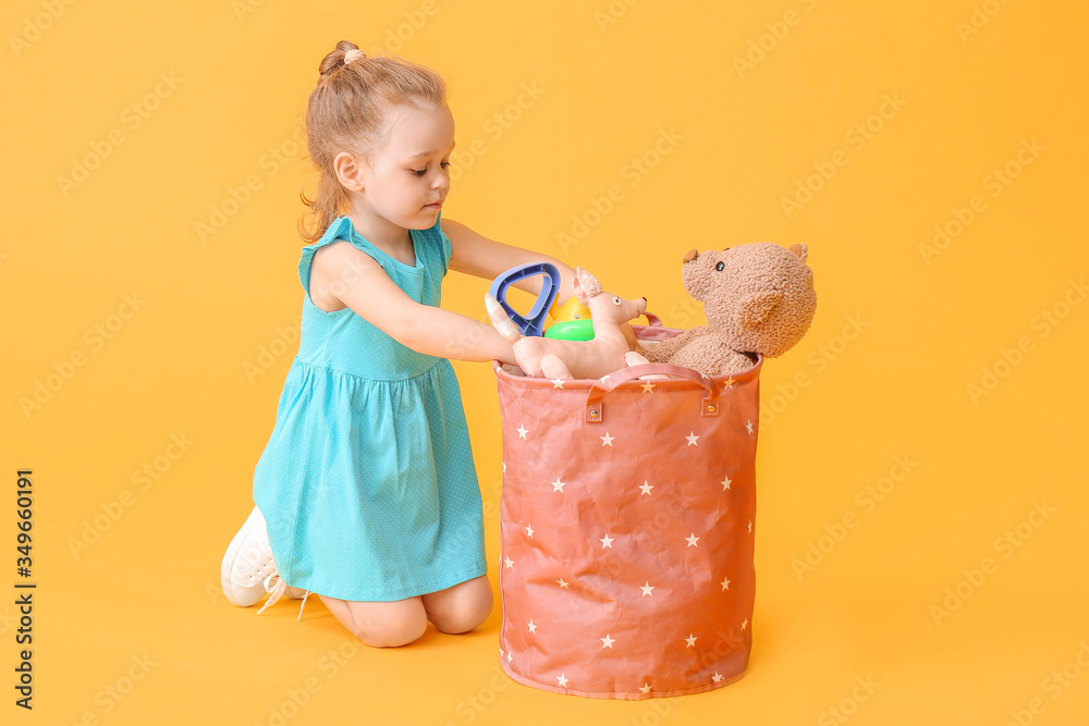 Little girl with toys on color background