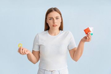 Sticker - Young woman with condoms on color background