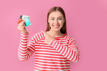 Sticker - Young woman with condoms on color background