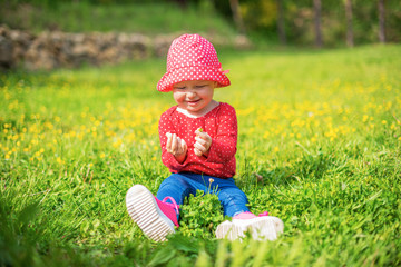 Wall Mural - Little girl plays on nature against the background of spring greenery.