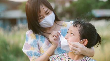 Mother help her daughter wearing face mask for protect 2019 - nCov , covid 19 or corona virus