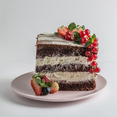 Wall Mural - Slice of chocolate sponge cake on a white plate with cream and berries side view