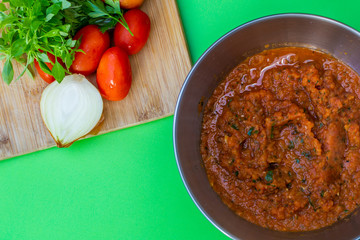 Tomato sauce .Composition on green background with bowl of fresh tomato sauce the ingredients, tomato, onion, basil are on the wooden board