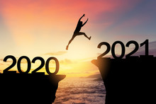 Silhouette Man Jumping Between Cliff With Number 2020 To 2021 At Tropical Sunset Beach. Freedom Challenge And Travel Adventure Holiday Concept.