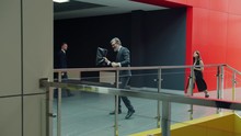 Slow Motion Of Grey-haired Business Man Dancing In Office Foyer Happy With Success And Achievements, People Colleagues Are Walking Around. Emotions And Work Concept.