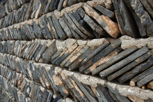 A Fence Made From Rows Of Slated Rock Layered With Cement