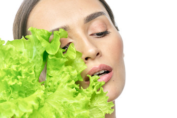 portrait of a girl with clean skin without makeup with a leaf of green salad