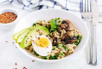 Breakfast oatmeal porridge with green herbs of mushrooms, boiled egg, avocado and flax seeds. Healthy balanced food.