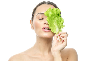 Wall Mural - portrait of a girl with clean skin without makeup with a leaf of green salad