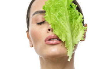 Wall Mural - portrait of a girl with clean skin without makeup with a leaf of green salad