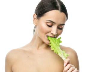 Wall Mural - portrait of a girl with clean skin without makeup with a leaf of green salad