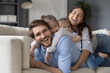 © fizkes - Overjoyed young Caucasian family with small daughters lying relaxing on cozy sofa in living room together, happy parents with little girls children rest cuddle hug on couch at home, show love and care