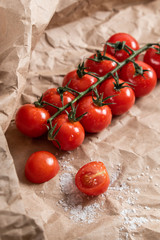 Fresh cherry tomatoes on a branch with salt lie on the background of craft paper. Top view with copy copy. Farming concept.