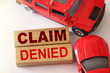 Claim denied words on wooden blocks and two red cars in road accident on white. Insurance concept, negative answer from insurance company