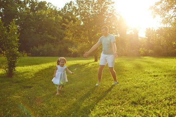 Wall Mural - Father's day. Father plays with his daughter in the summer park.