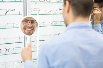Fototapete - Happy man choosing glasses at optics store