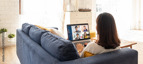 Fototapeta na szkło Young Asian businesswoman work at home and virtual video conference meeting with colleagues business people, online working, video call due to social distancing at home office