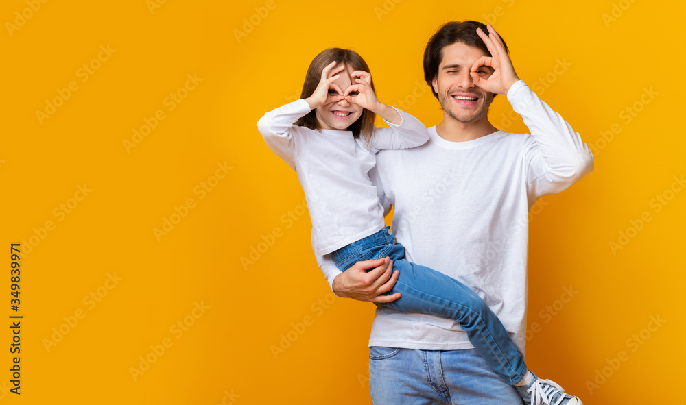 Joyful dad and daughter having good time over yellow background - obrazy, fototapety, plakaty 