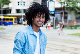 Fototapeta Uliczki - Mexican young adult man with long curly hair outdoor in city