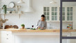 © fizkes - Young Caucasian woman stand at modern design kitchen counter cooking vegetable salad drinking wine, millennial girl female tenant or renter prepare vegetarian food in beautiful renovated home