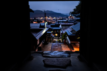 Takayama, Japan Gifu prefecture in Japan with view of skyline cityscape framing from temple entrance of mountain town village in dark night with illuminated buildings