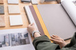 © pressmaster - Hands of young contemporary designer looking through samples of wallpapers