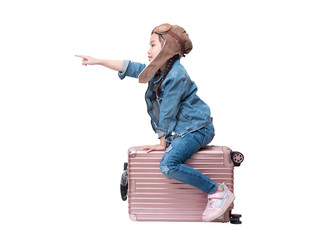 Asian little cute girl 6 years old wear pilot hat and sitting on pink luggage with pointing finger isolated on white background with clipping path.