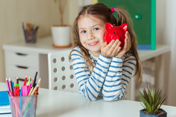 Education, school and money saving concept - child holds a red piggy Bank