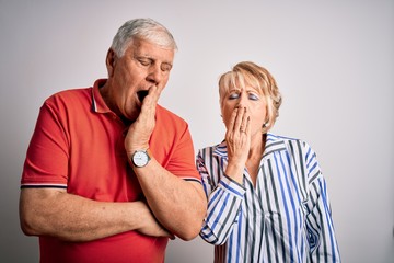 Wall Mural - Senior beautiful couple standing together over isolated white background bored yawning tired covering mouth with hand. Restless and sleepiness.