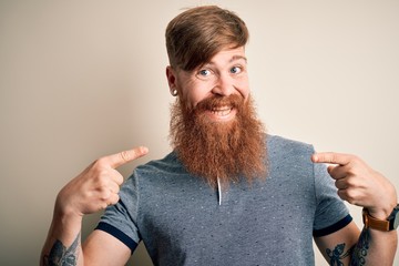 Poster - Handsome Irish redhead man with beard and arm tattoo standing over isolated background looking confident with smile on face, pointing oneself with fingers proud and happy.