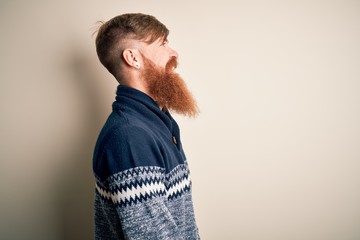 Canvas Print - Handsome Irish redhead man with beard wearing winter sweater over isolated background looking to side, relax profile pose with natural face with confident smile.