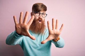 Sticker - Handsome Irish redhead man with beard wearing glasses over pink isolated background doing stop gesture with hands palms, angry and frustration expression